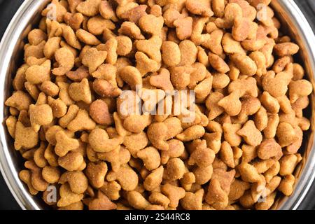 Cat food in bowl isolated on white background. Brown cat kibble. Flat lay, Top view Stock Photo