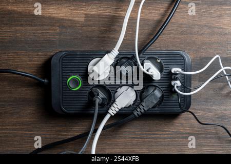 AC outlet multiprise power strip with USB plugs at home. Electrical plug in outlet socket at home. Energy efficiency concept. Black plastic power stri Stock Photo