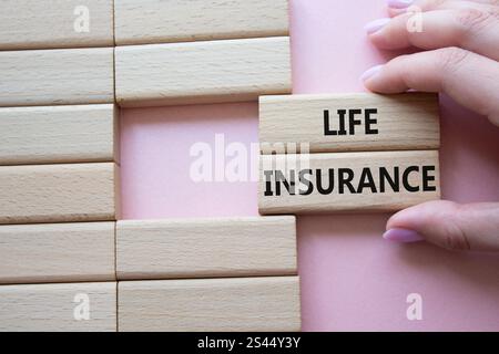 Life insurance symbol. Concept word Life insurance on wooden blocks. Businessman hand. Beautiful pink background. Business and Life insurance concept. Stock Photo