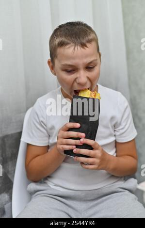 boy eats delicious shawarma with an appetite. Stock Photo