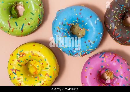 Colorful glazed donuts with sprinkles on pastel background Stock Photo