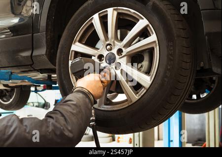 Mechanic using an impact wrench to change a car wheel in a professional garage Stock Photo
