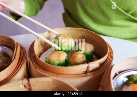 Closeup of Shumai, Shrimp and Pork Filled Chinese Steamed Dumpling Being Picked with Chopsticks Stock Photo
