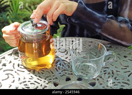 Woman preparing hot tea to serve on garden table Stock Photo