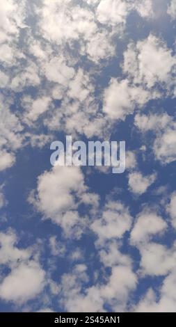 White fluffy clouds are forming on a deep blue sky, bringing the promise of a beautiful sunny day Stock Photo