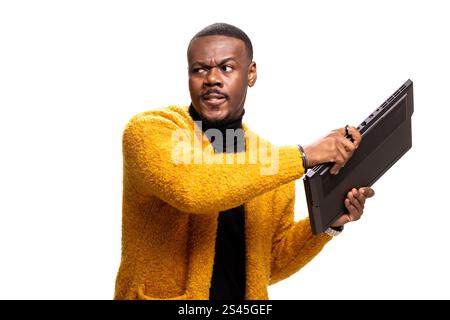 A man humorously holding a computer keyboard while wearing a cozy mustard sweater. This studio shot captures a playful expression on his face, offerin Stock Photo