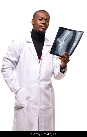 Doctor wearing a white coat examines an x-ray image of a knee, showcasing professionalism in a clinical setting, focusing on diagnosis and patient car Stock Photo