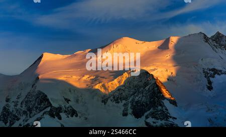 Snow-capped mountains illuminated by the last of the setting sun Stock Photo