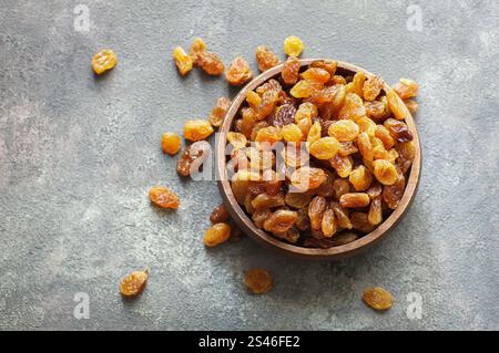 Dried grapes in wooden bowl or scoop on rustic background, healthy dry fruit concept, raisins Stock Photo