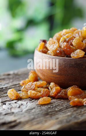Dried grapes in wooden bowl or scoop on rustic background, healthy dry fruit concept, raisins Stock Photo