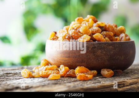 Dried grapes in wooden bowl or scoop on rustic background, healthy dry fruit concept, raisins Stock Photo