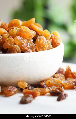 Dried grapes in wooden bowl or scoop on rustic background, healthy dry fruit concept, raisins Stock Photo