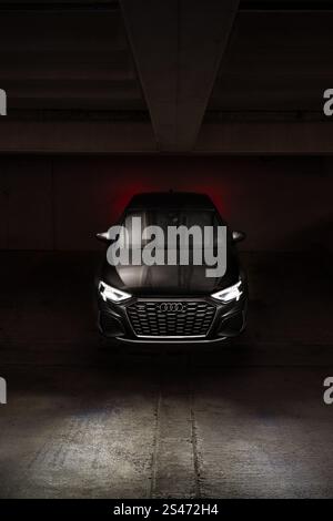 Front view of Audi S-line car in dark underground parking garage with headlights on and dramatic lighting. Stock Photo