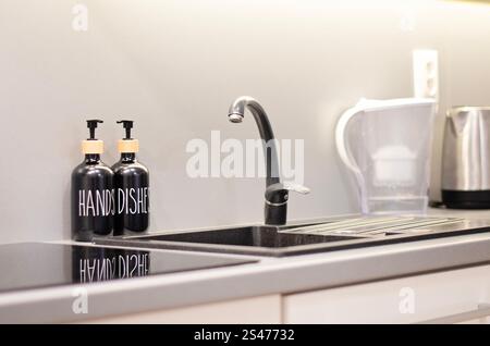 Black and grey kitchen close up with built in stove and sink. Clean kitchen workspace. Stock Photo