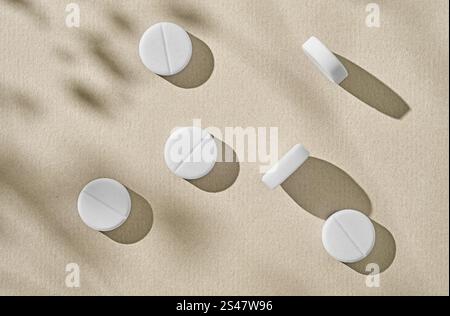 white pills on sunny beige background, top view Stock Photo