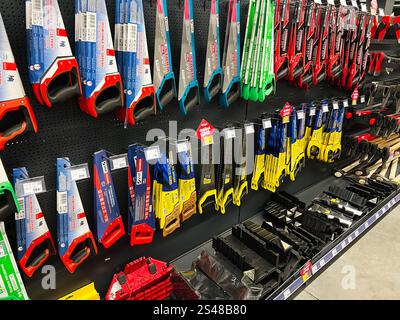 Kyiv, Ukraine - January 10, 2025: Various colored hand saws arranged neatly on a shelf in a tools store, showcasing different sizes and designs for wo Stock Photo