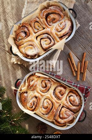 Homemade cinnamon rolls in two enameled baking pans with Christmas decoration, top view Stock Photo