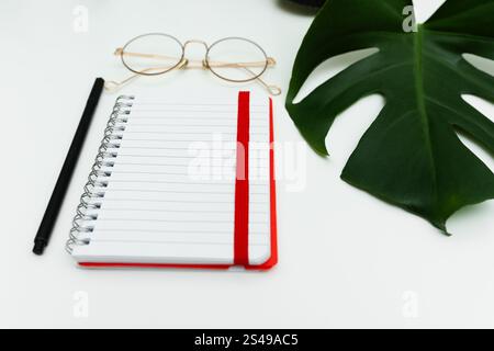 open red notebook with pencil and glasses. school notebook on white background, spiral notepad on table Stock Photo