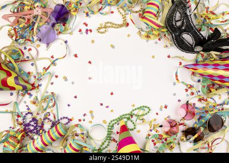 Colourful carnival paraphernalia such as hats, masks and confetti on a white background Stock Photo