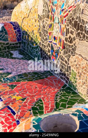 A mosaic bench with a hand on it. The bench is colorful and has a unique design. The hand on the bench is red and green, and it seems to be reaching o Stock Photo