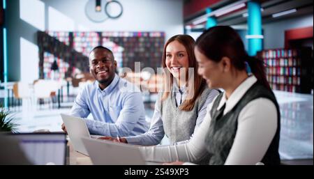 Students Learning Online At University Library Using Laptops Stock Photo