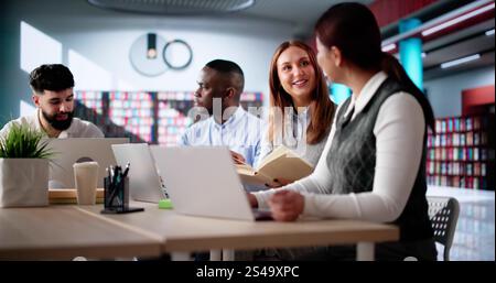 Students Learning Online At University Library Using Laptops Stock Photo
