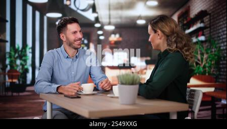 Laughing Male And Female Sitting In Cafe Drinking Coffee And Talking Stock Photo