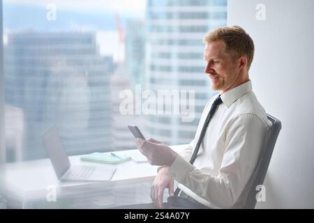 Busy happy professional business man using cellphone working in office. Stock Photo