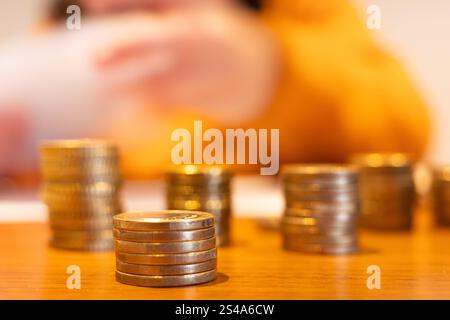 Closeup of stacks of coins on wooden table with blurred background representing finance and saving money Stock Photo