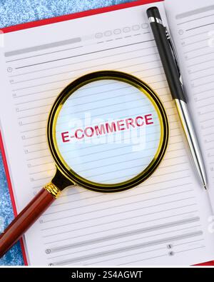 E-COMMERCE - activity of electronically buying or selling of products on online services. E-COMMERCE word in the business notebook. Copy space. Stock Photo