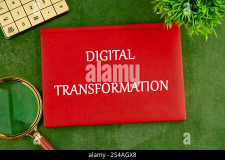 Digital transformation and digitalization technology. DIGITAL TRANSFORMATION on the cover of a red notebook on a green saturated background. Stock Photo