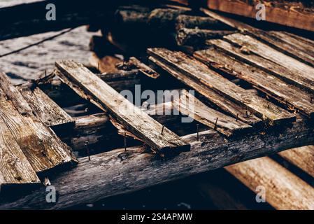 Old rusty nails sticking out of a wooden collapsed bridge, structural repair Stock Photo