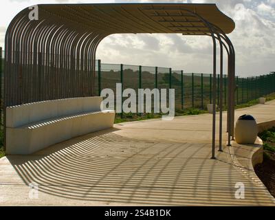 Modern Outdoor Bench With Metal Shade and Unique Shadow Patterns Stock Photo
