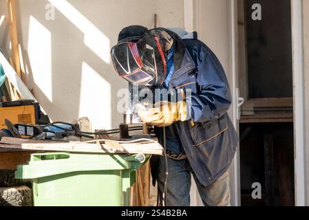 Male welder working on construction site, worker builder making weld Stock Photo