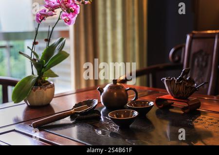 Tea set on the wooden table in authentic vintage style with orchid flower at the background - dark und moody photography Stock Photo