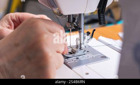 A detailed close up of an individual skillfully using a sewing machine, demonstrating precise techniques and creativity in fabric work Stock Photo
