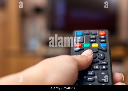 A person is currently holding a remote control device firmly in their hand as they prepare to use it for electronic purposes Stock Photo