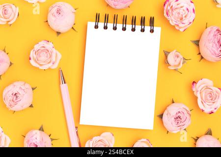 Blank notepad mockup. Stationery and pink rose flowers on a yellow background. Stock Photo