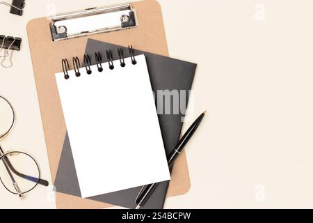 Workspace with clean notepad mockup, eyeglasses and stationery on a beige background. Notebook template. Stock Photo