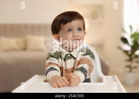 Cute little kid sitting in high chair at home Stock Photo