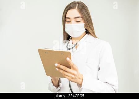 Doctor woman taking notes on clipboard. Close-up of a unrecognizable female professional filling up come medical form Stock Photo