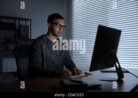 Programmer working on computer indoors at night Stock Photo