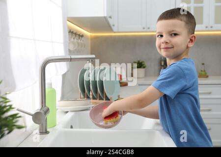 Little helper. Cute boy washing dishes at home Stock Photo