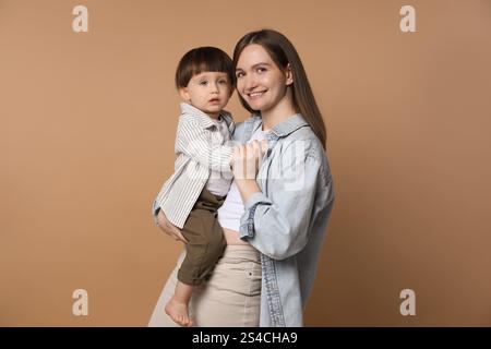 Family portrait of happy mother with her little son on beige background Stock Photo