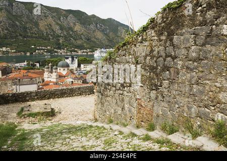 High angle view of walled mountainside walking trail and old stone wall, apartment buildings and houses covered with traditional terracotta clay roof Stock Photo