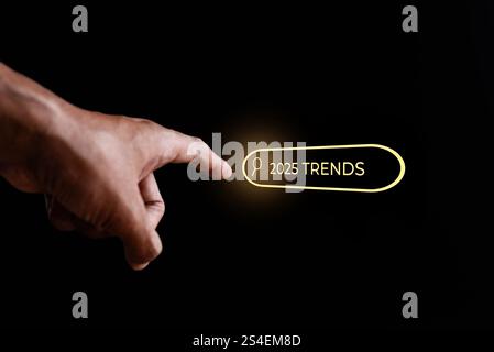 A close-up image of a hand touching a glowing button labeled "2025 Trends." Exploration and discovery of upcoming trends concept. Stock Photo
