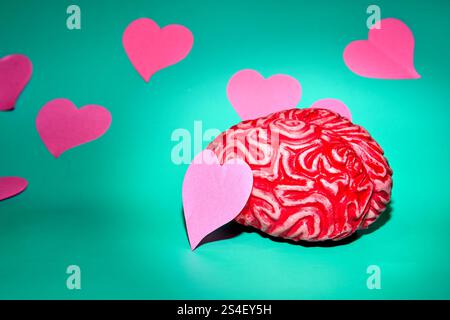 red brain surrounded by pink hearts against a teal colored Stock Photo