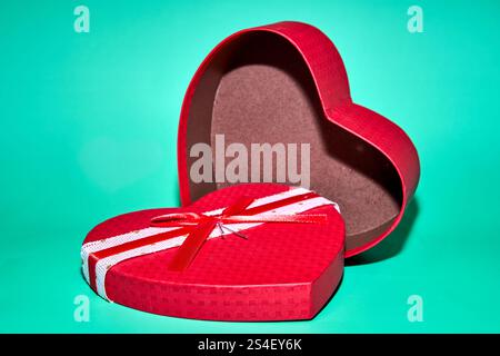 red heart shaped box, open, on a teal background Stock Photo