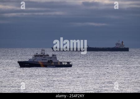 Sassnitz, Germany. 12th Jan, 2025. The unmaneuverable tanker "Eventin" is lying in the Sassnitz roadstead between Binz and Sassnitz. The tanker, loaded with around 99,000 tons of oil, is to remain there until a decision has been made on how to proceed. The federal police vessel BP82 "Bamberg" sails in front of the oil tanker. Credit: Stefan Sauer/dpa/Alamy Live News Stock Photo