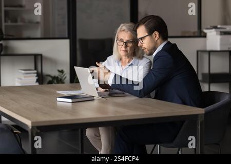 Male female colleagues using modern laptop at workplace Stock Photo